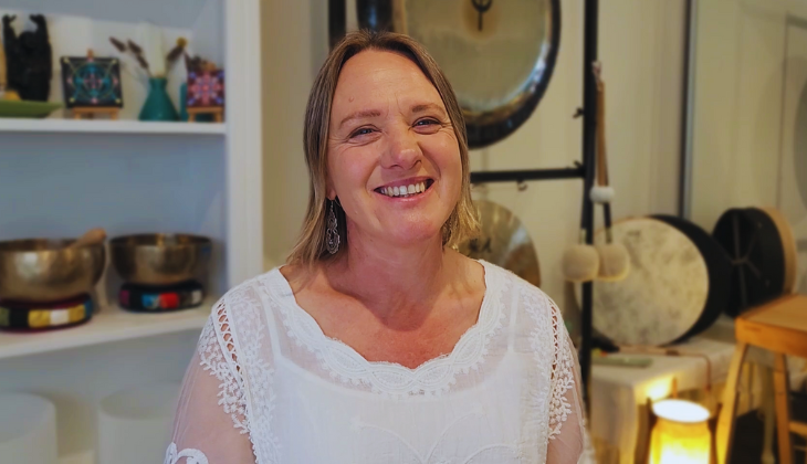 Lisa in her therapy room with crystal bowls and gongs, creating a relaxing environment for sound healing.