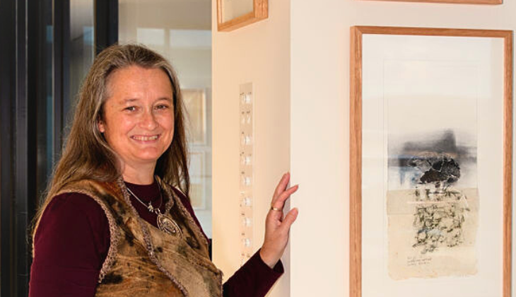 Cinnamon Stephens standing beside curated art pieces from local Surf Coast artists.