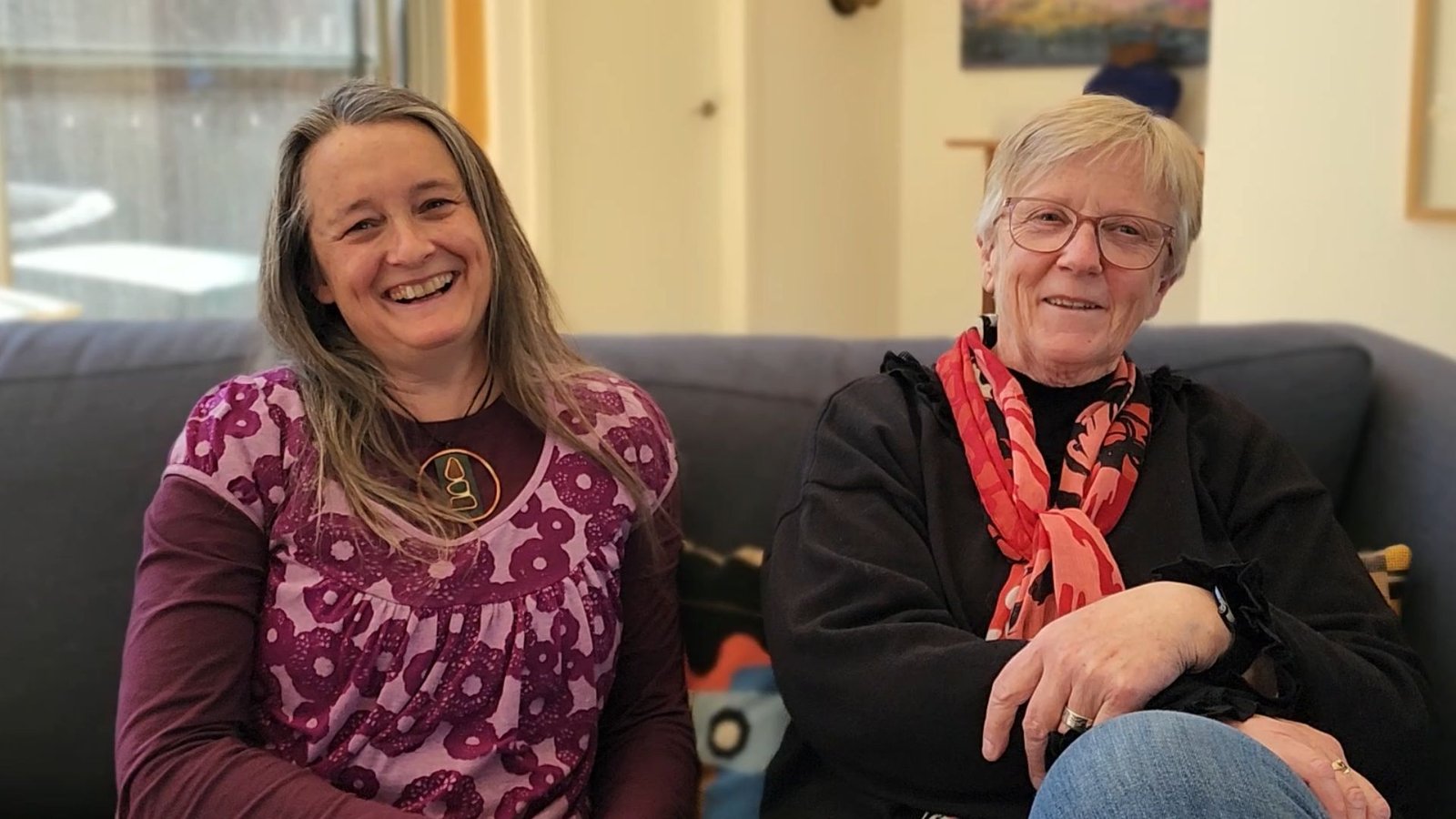 Local artist Deb and Cinnamon from Cinnamon's Art Consultancy sitting together on a couch, engaging in conversation, representing the supportive connection they share.