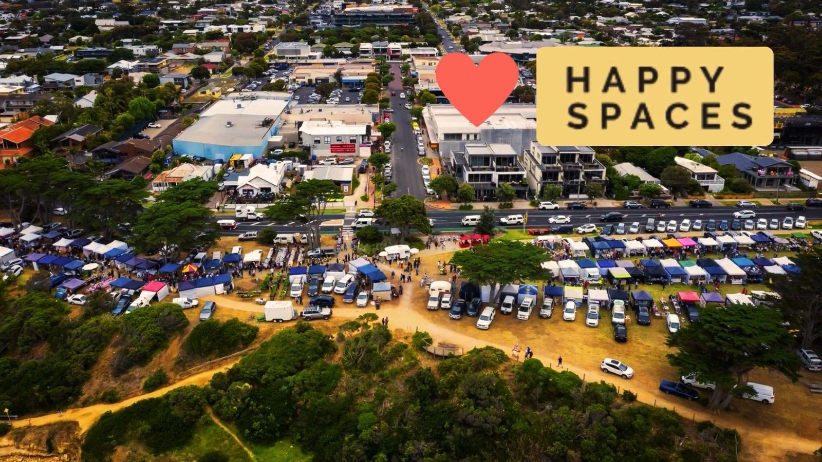 Aerial view of Torquay showing Happy Spaces' location near the coast and a lively community market, illustrating its connection to the local area.