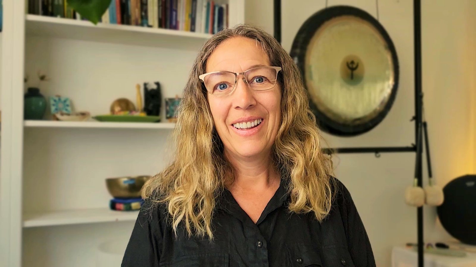 Portrait of Kim smiling warmly in Lisa's Torquay sound healing room, feeling rested and supported as shared in her customer story.